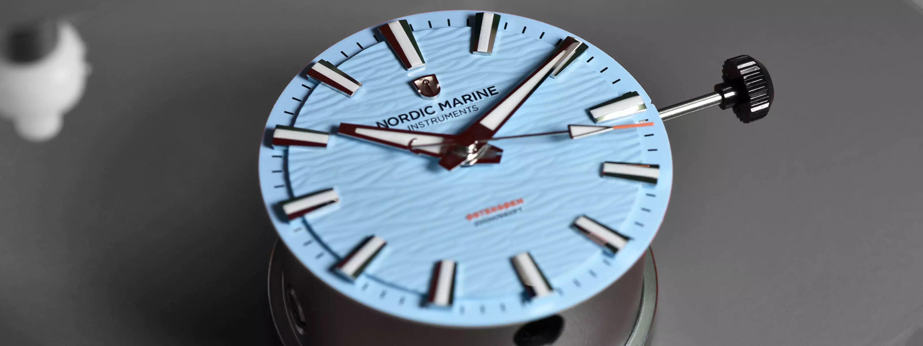Close-up of a blue watch wave dial with Nordic Marine Instruments brand logo on watchmaker tool