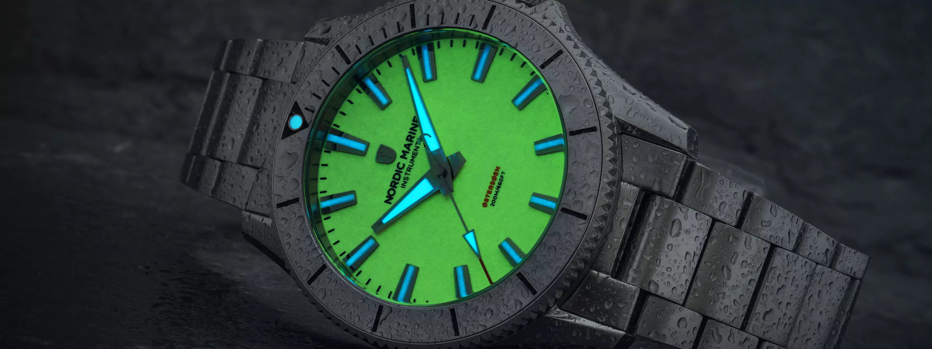 Dive watch with a glowing green full lume dial and wet stainless steel bracelet on a dark background
