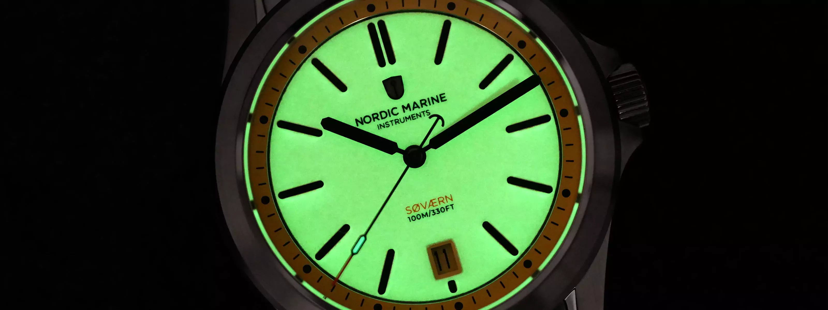 Nordic Marine Instruments watch with a glowing green full lume dial on a black background